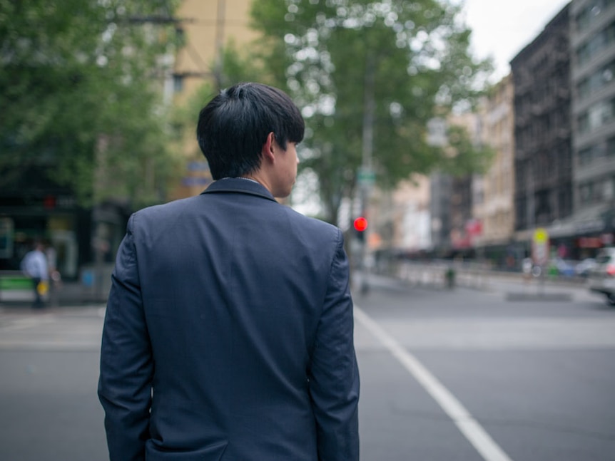 A businessman waits to cross the road in Melbourne.