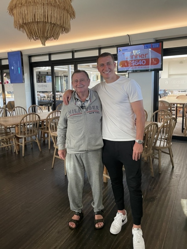 A photo of a dad wearing a grey tracksuit and his son