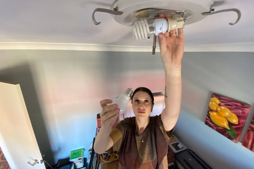 A woman changes the lightbulb indoor.
