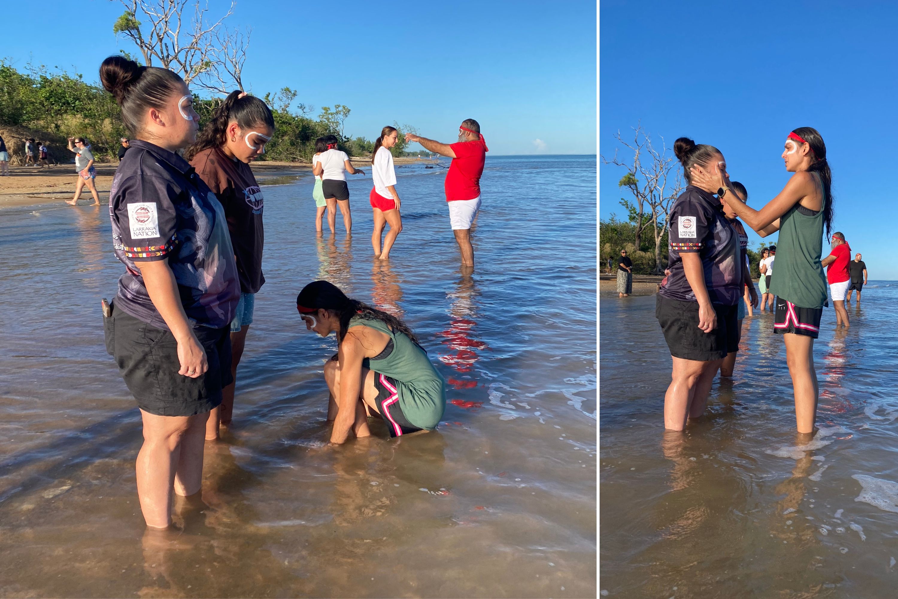 People standing at the edge of the water on a beach, gathered in small groups.