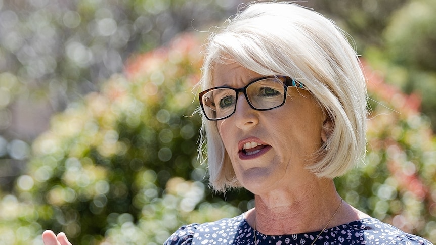 a woman wearing glasses with short hair looking to the left