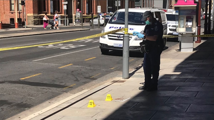 A policeman takes photos of the ground at a crime scene