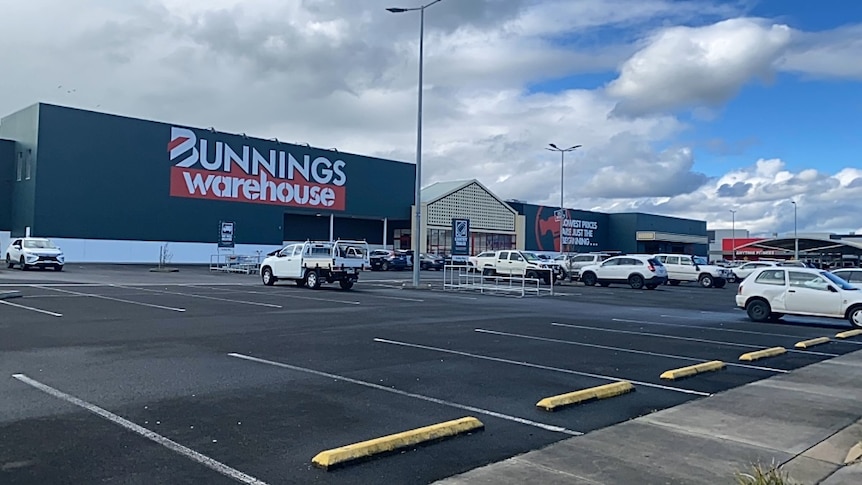 Cars parked in front of a big shed painted with the words "Bunnings Warehouse"