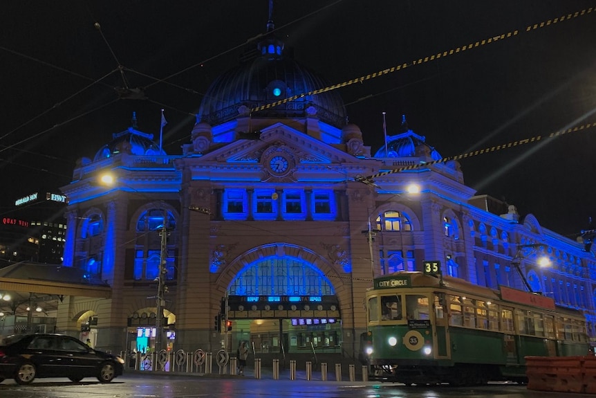 Flinders Street Station's exterior is lit up in blue lights.