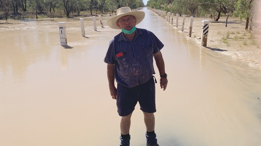 A man stands in front of floodwaters