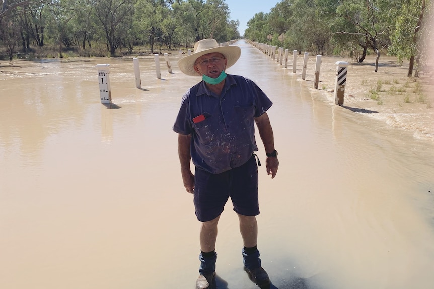 A man stands in front of floodwaters