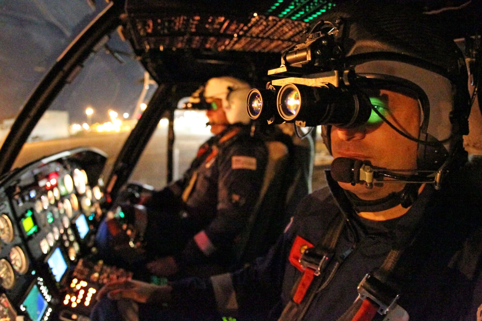 Two men sitting in a helicopter at night 