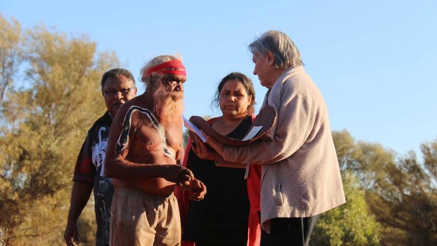 Four people stand in the bush in Central Australia