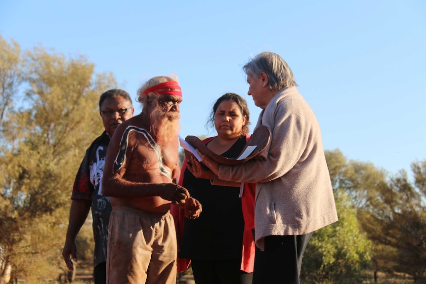 Four people stand in the bush in Central Australia