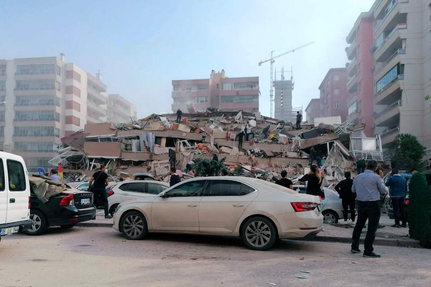 People climb over the rubble of a collapsed building.