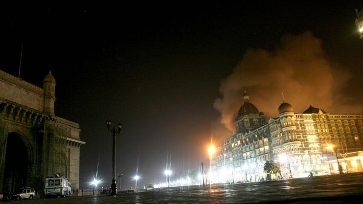 Smoke billows from Taj Hotel in front of the historic Gateway of India, left, in Mumbai