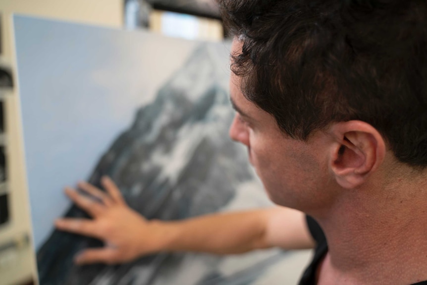 A close up of a man working with his hands on a canvas