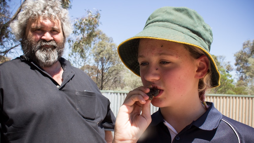 Loxton North Primary School student Lily gets her first taste of kangaroo tail as Chris Koolmatrie awaits her reaction.