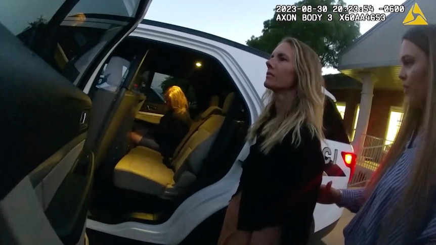 Bodycam footage shows two long-haired women being taken to a car with its door open