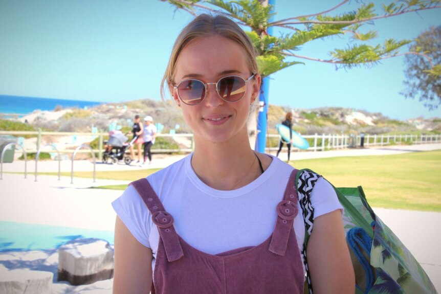 A woman with sunglasses stands under a tree