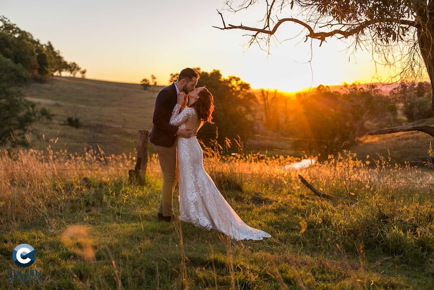 An unknown bride and groom kissing in a field