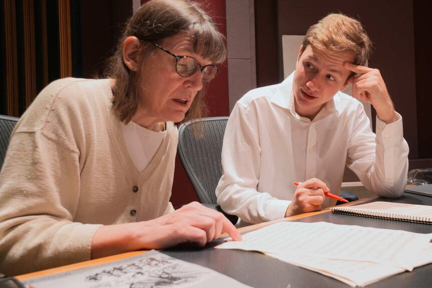 Professor Patricia Hall, left, and graduate student Joshua Devries, right, sit at a desk as they review sheet music together.