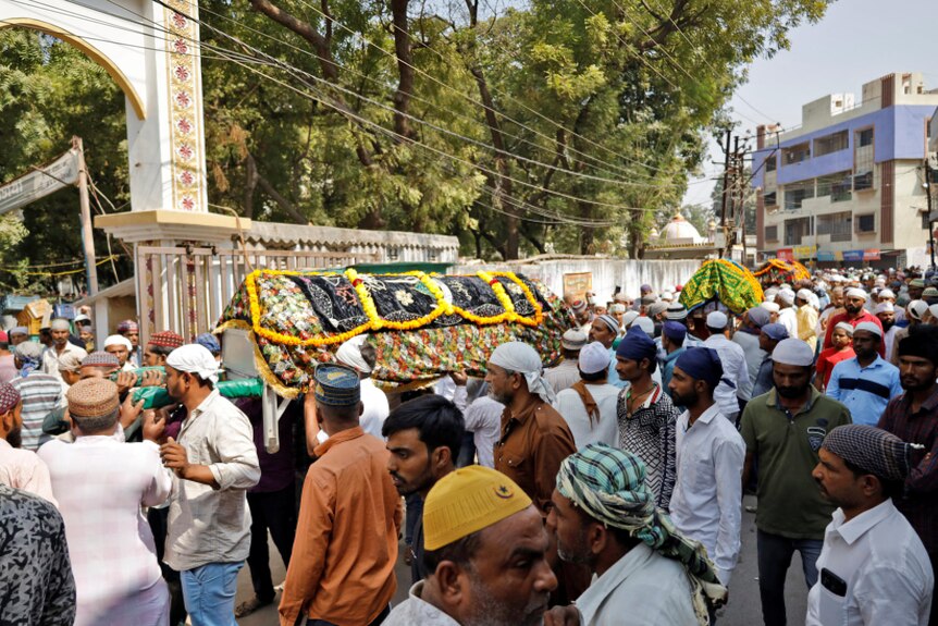 A crowd with people carry coffins.