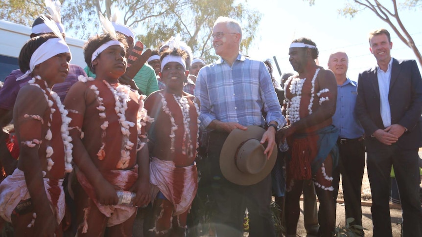 Malcolm Turnbull stands with Indigenous performers in traditional dress at Tennant Creek.