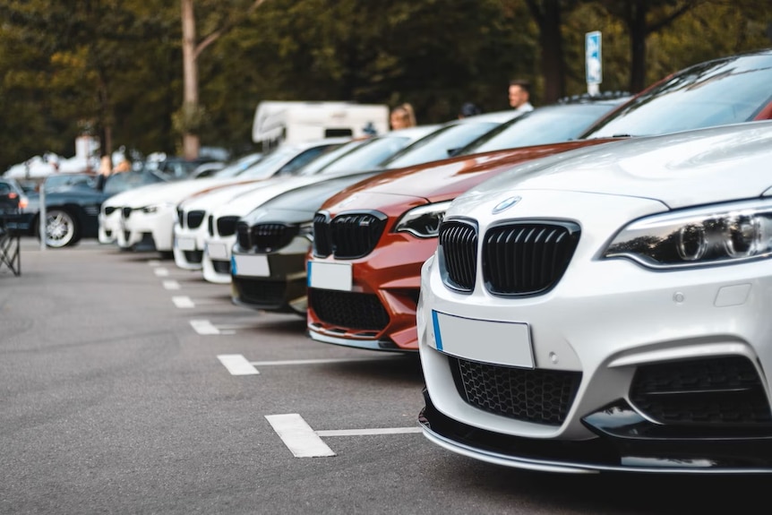 A row of about seven new-looking cars reversed into car parks in a line next to each other.