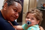 An Indigenous woman and a toddler look at the camera for a photo.