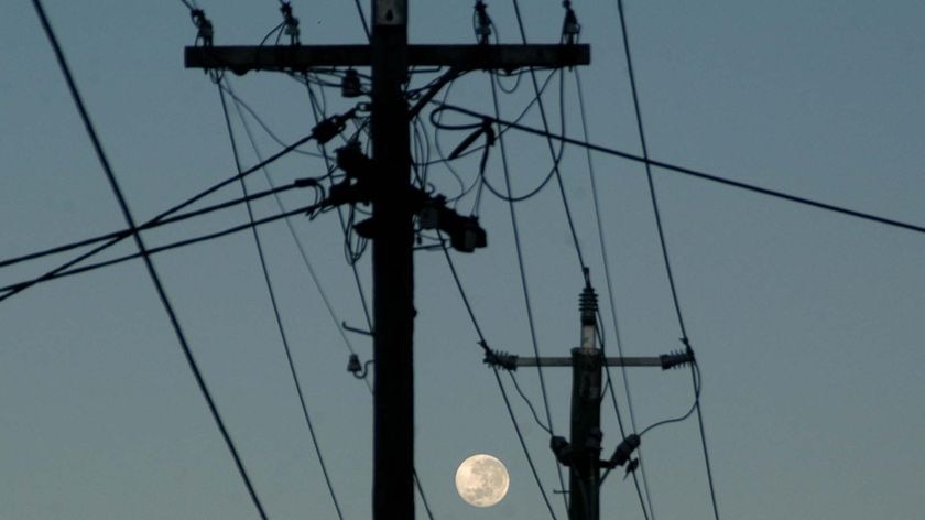 The full moon rises through powerlines