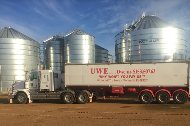 A truck painted with "UWE... owe us $153,000"