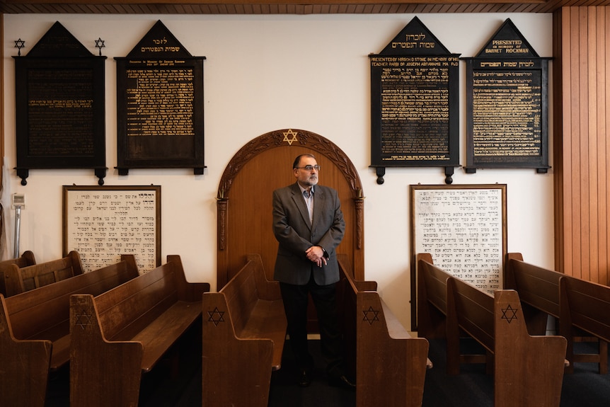 A man in a suit standing in a room filled with pews