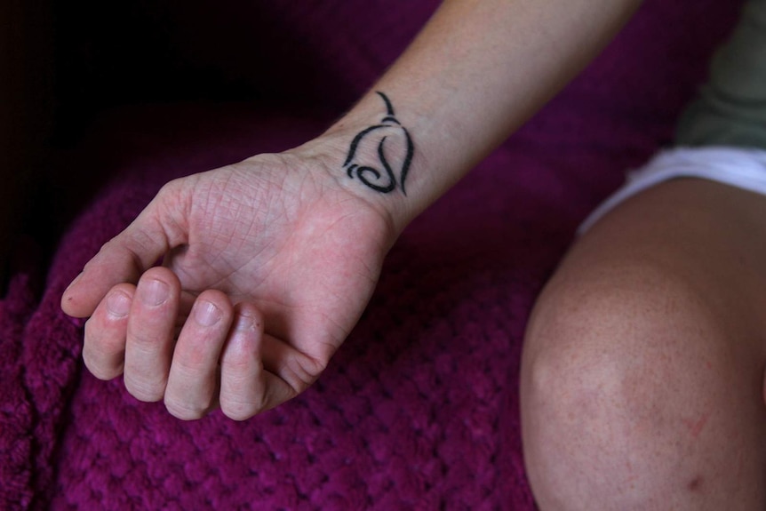 A photo of Justine Clason's wrist, which is tattooed with a rose.