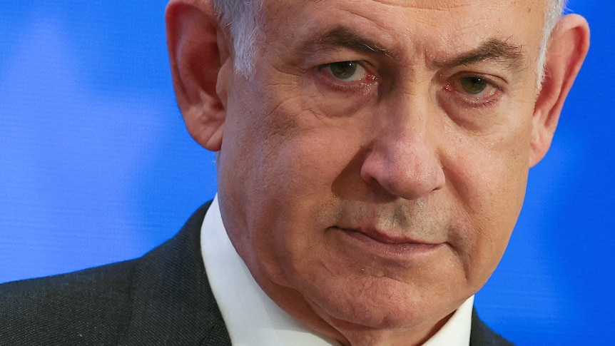 Benjamin Netanyahu wears a suit and white shirt looking sternly