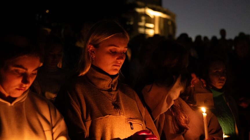 young women hold candles at the victims of bondi stabbing on 210424