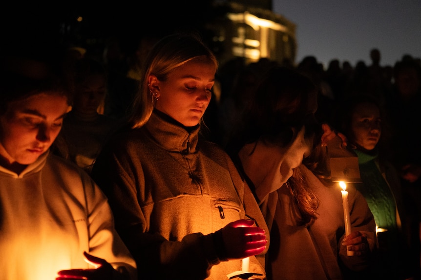 young women hold candles at the victims of bondi stabbing on 210424