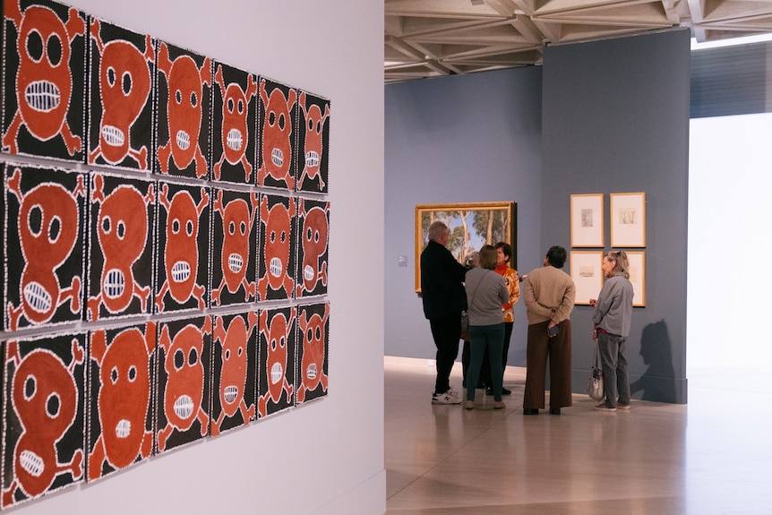 People talk in an art gallery displaying Indigenous work