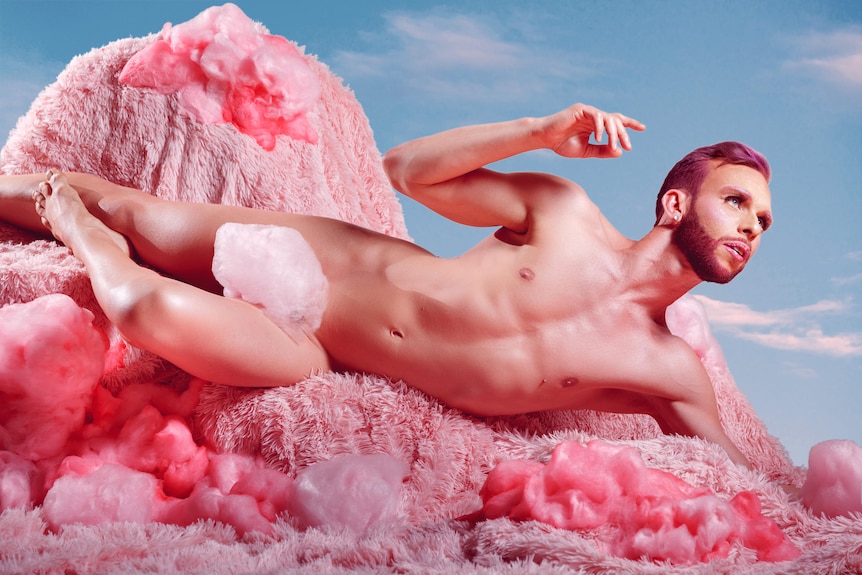 A man sprawling naked on a pink cloth with fairy floss.