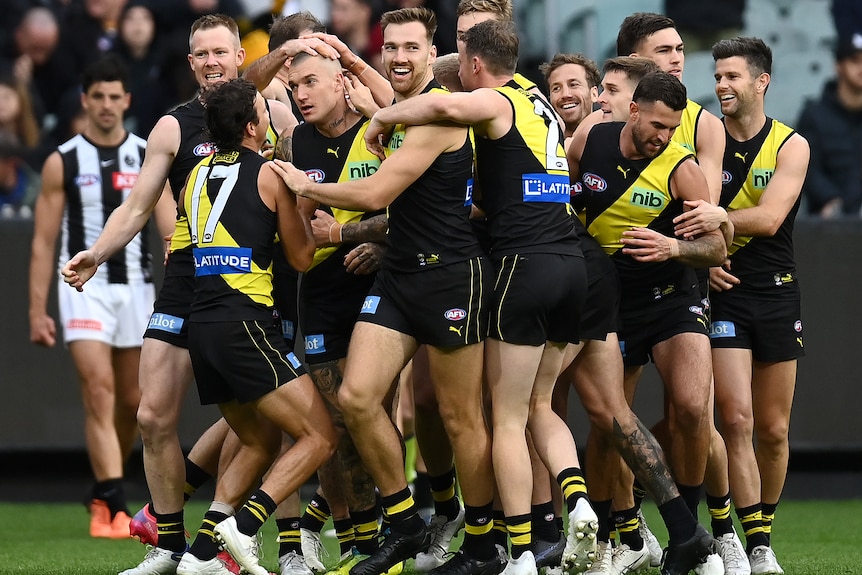 A large group of players from Richmond gather around Dustin Martin to congratulate him