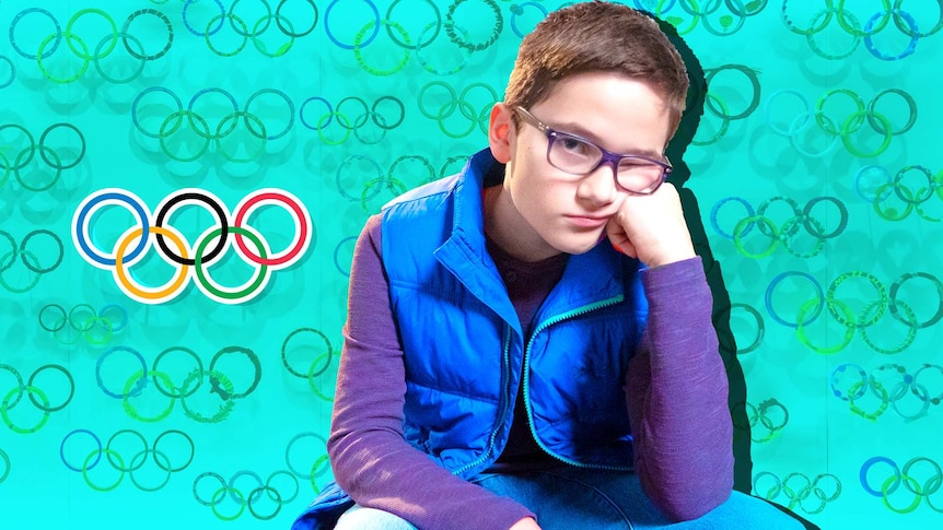 A boy sits with his hand on his faced looking bored. Many Olympic rings logos like a wallpaper behind him.
