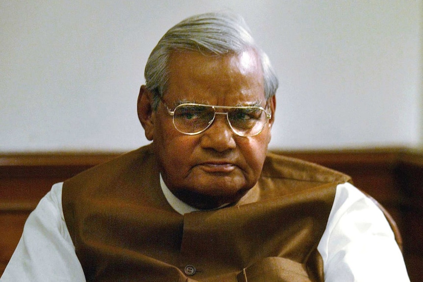 Atal Bihari Vajpayee sits with his arms crossed and a plain look on his face.