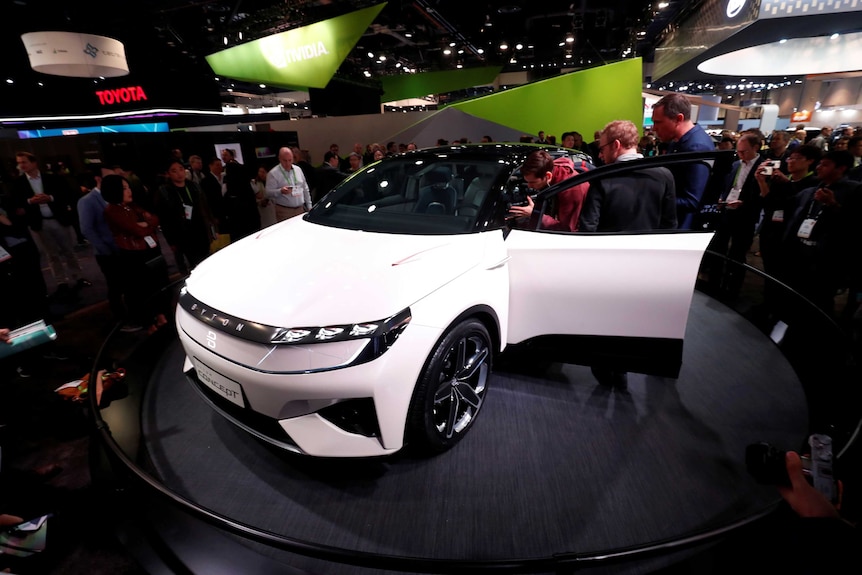 A white Byton electric car is displayed on a show floor