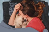 Kate Leaver lying down and cuddling her dog in a story about how to maintain your friendships through a difficult time