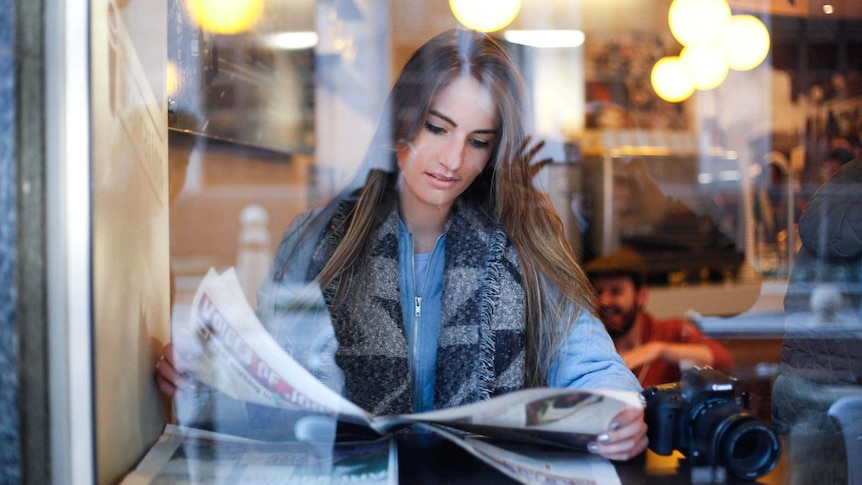 Woman reading newspaper in cafe