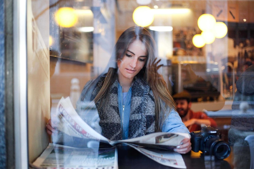 Woman reading newspaper in cafe