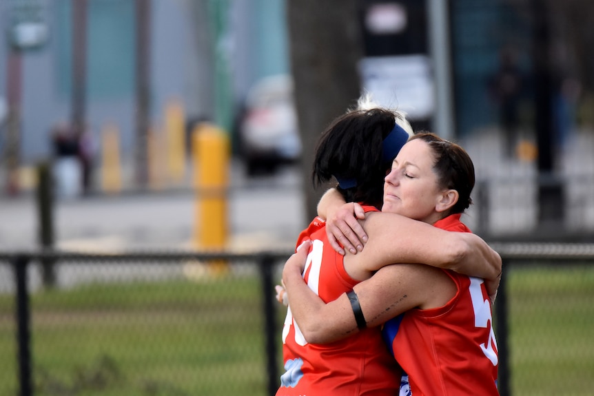 Two female Aussie Rules players embrace at the end of the game.