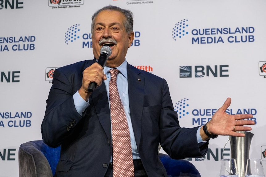 El presidente de los Juegos Olímpicos de Brisbane, Andrew Liveris, habla por un micrófono.