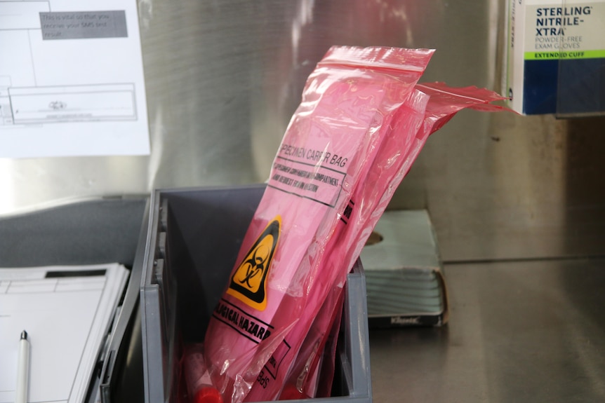 Queensland Ambulance Service's COVID-19 saliva tests sitting in red hazard bags in a tray.