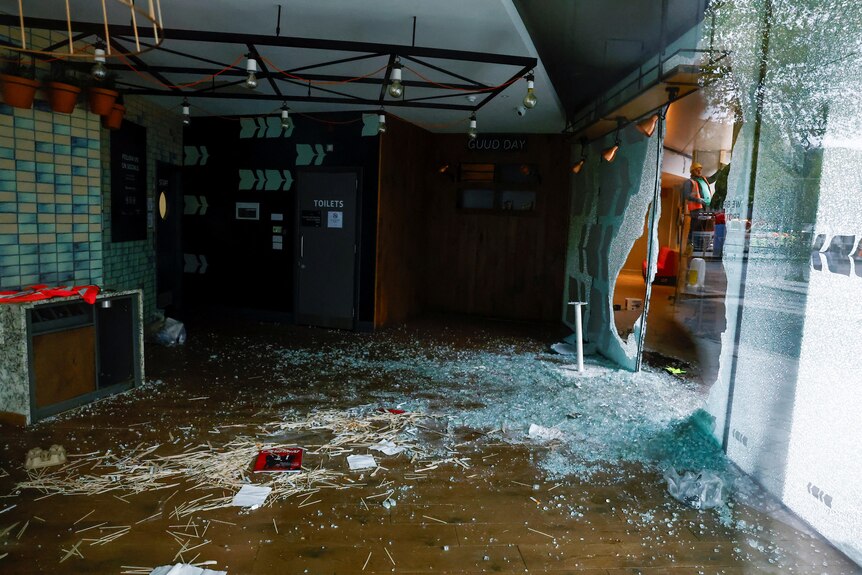 A store with the window shattered and spread all over the floor.