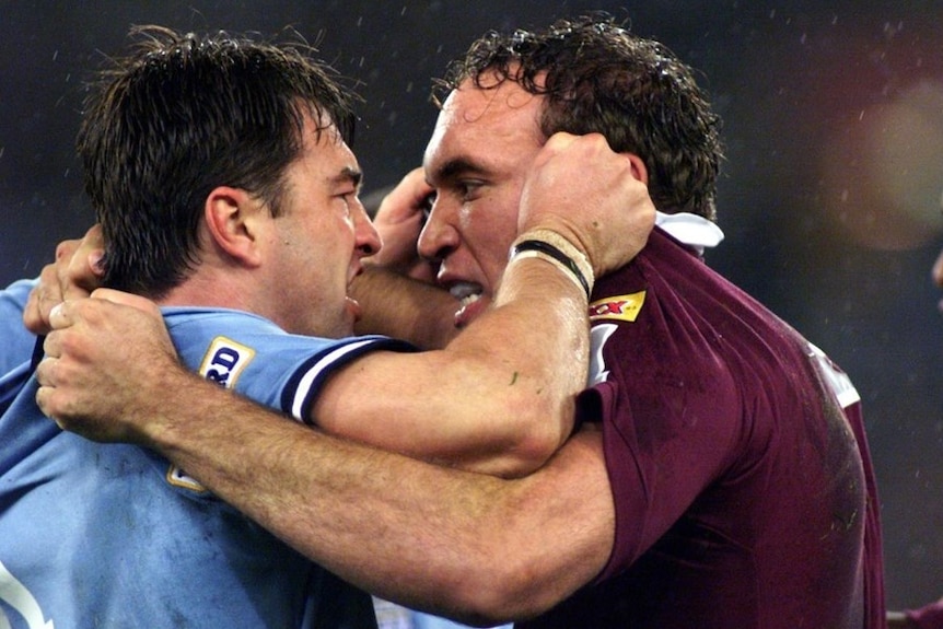 Two rugby league players hold each others' jersey, angrily gesturing, trying to intimidate the other