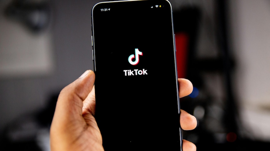 A generic image of a person holding a phone with TikTok loaded on the screen.