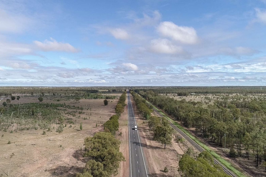 An aerial image of a country highway and white school bus