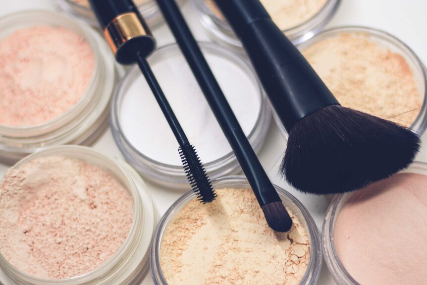 An image of a collection of fair-colour makeup powders, with brushes on top.