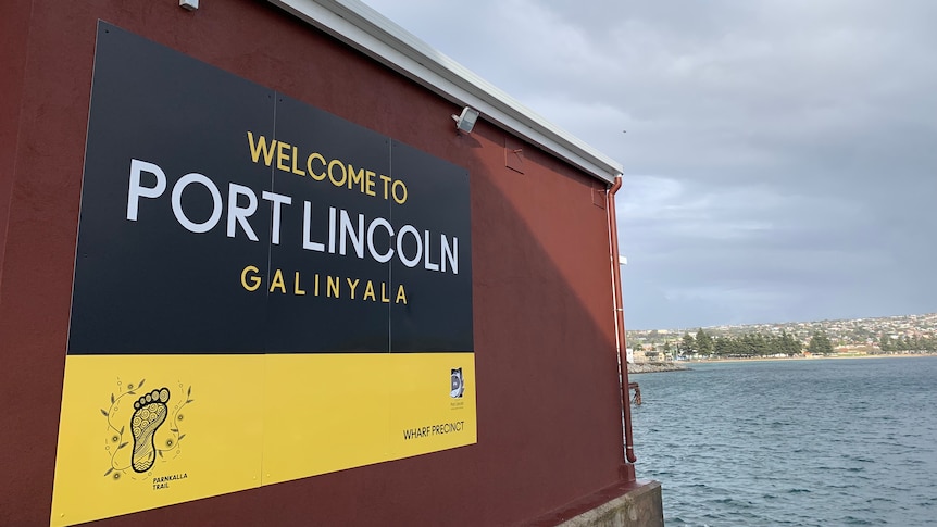 a big sign that reads "Welcome to Port Lincoln GALINYALA" with water in the background